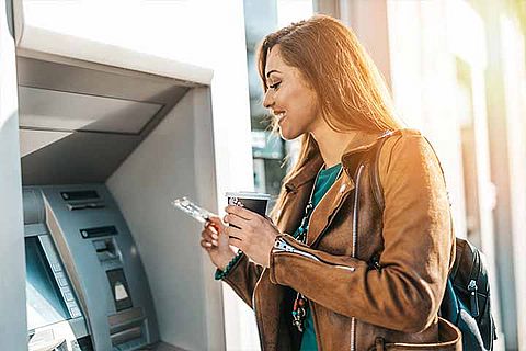 Lächelnde Frau am Geldautomaten
